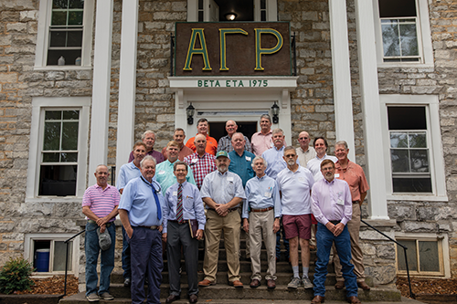 Group of alumni and friends in front of the Alpha Gamma Rho fraternity house