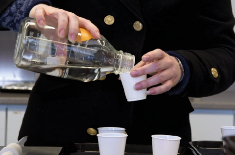 Image of a person pouring whiskey into dixie cups