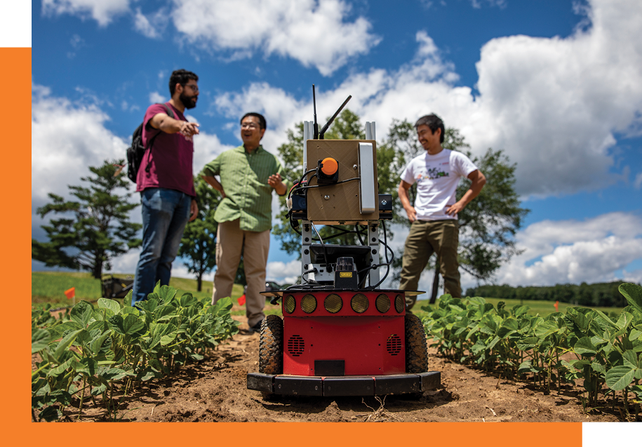 Image of the three students in a field with a robot